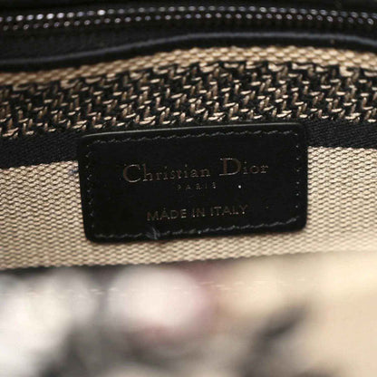 Leather brand patch reading Christian Dior and Made in Italy on canvas bag.
