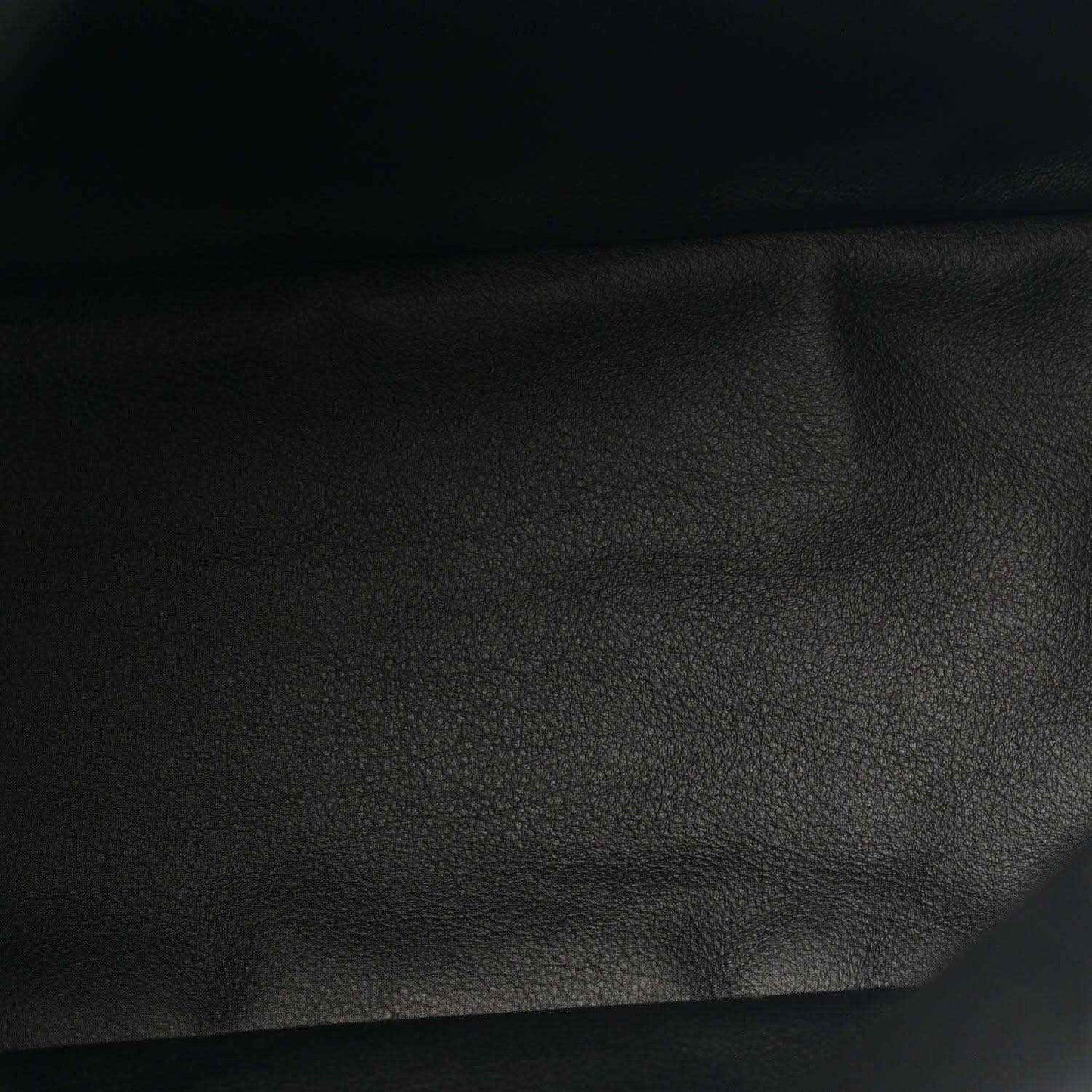 Black leather panel close-up with pebbled texture from a reversible tote bag