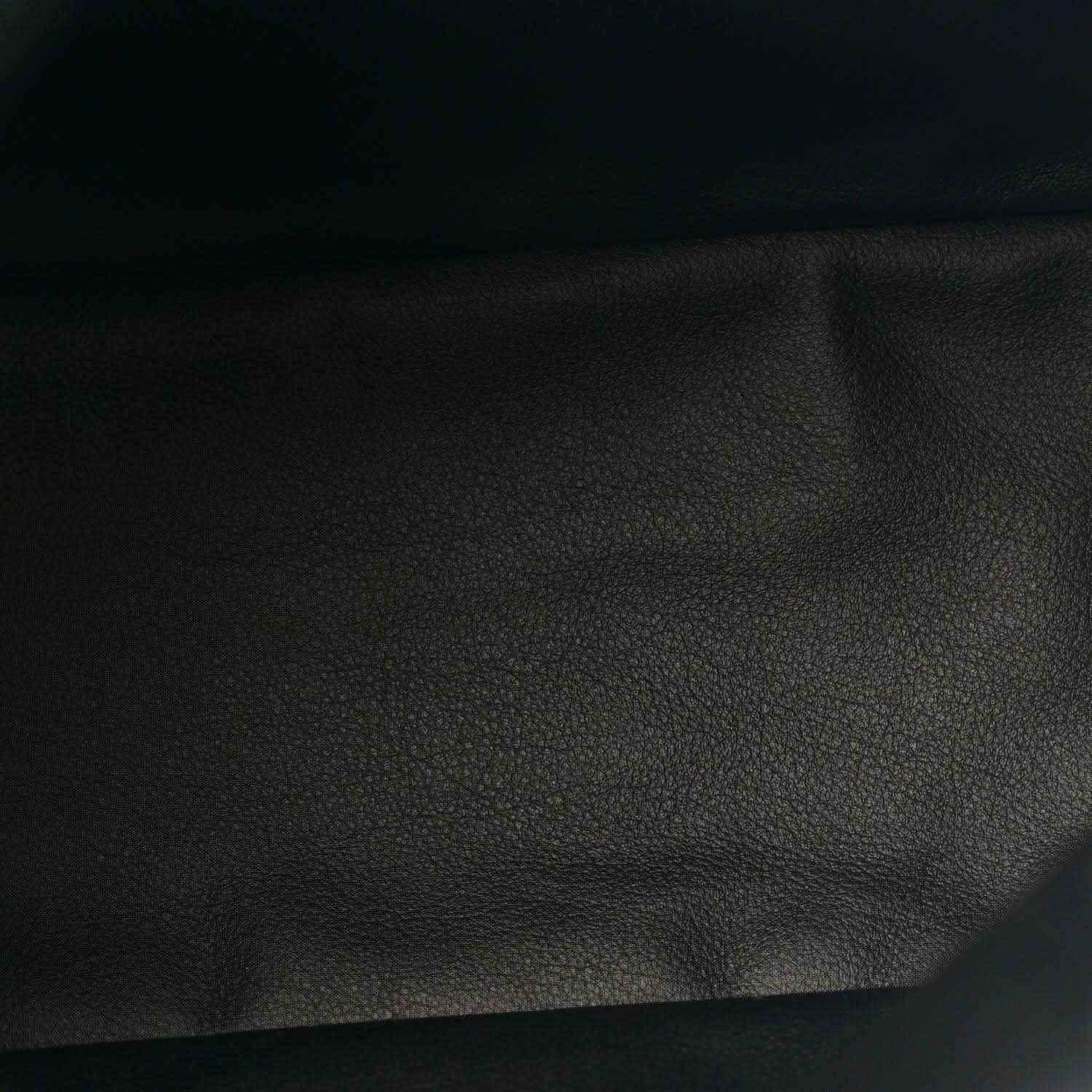 Black leather panel close-up with pebbled texture from a reversible tote bag
