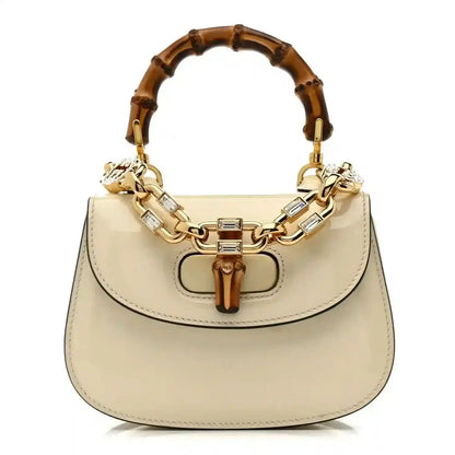 White mini handbag with bamboo-style handle and gold chain strap, top clasp