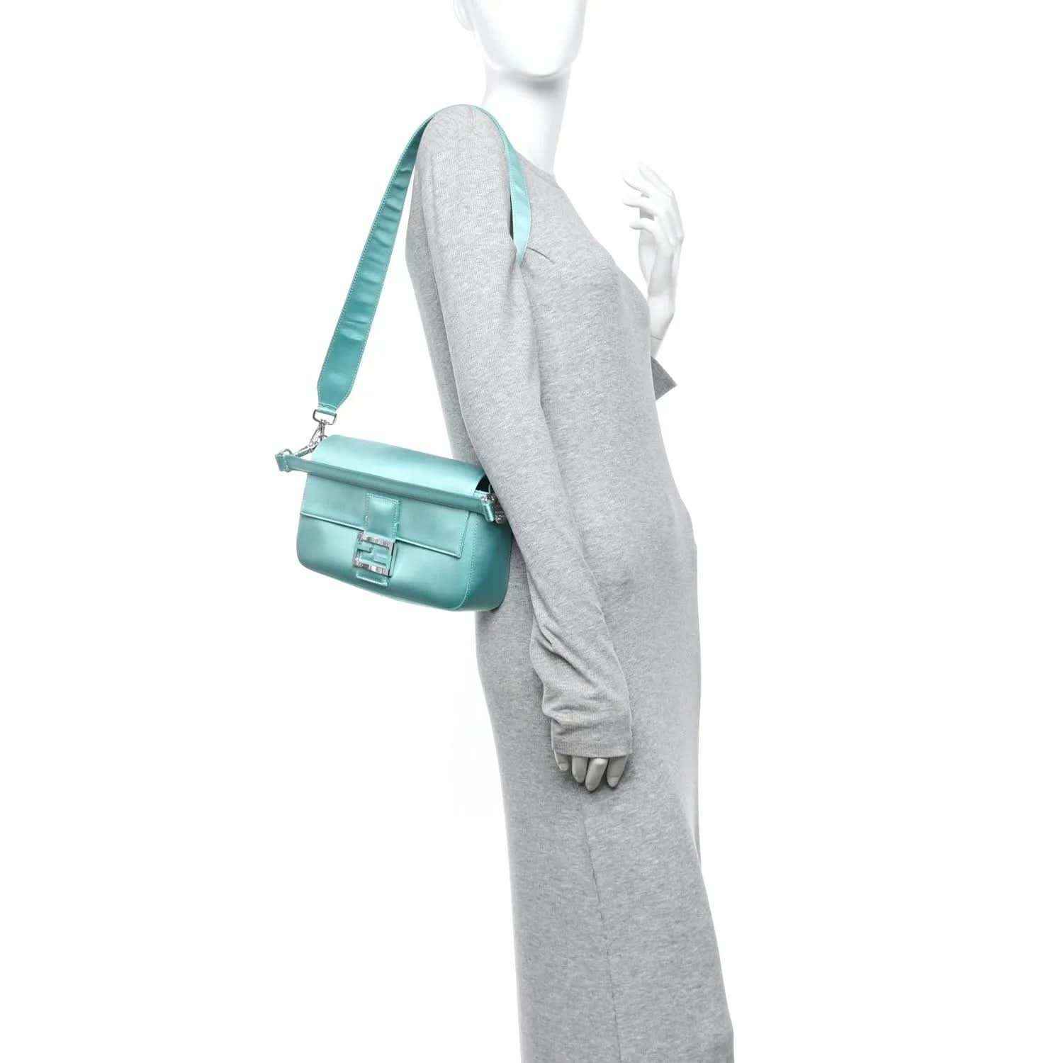 Blue baguette bag with shoulder strap and flap clasp, worn crossbody on model
