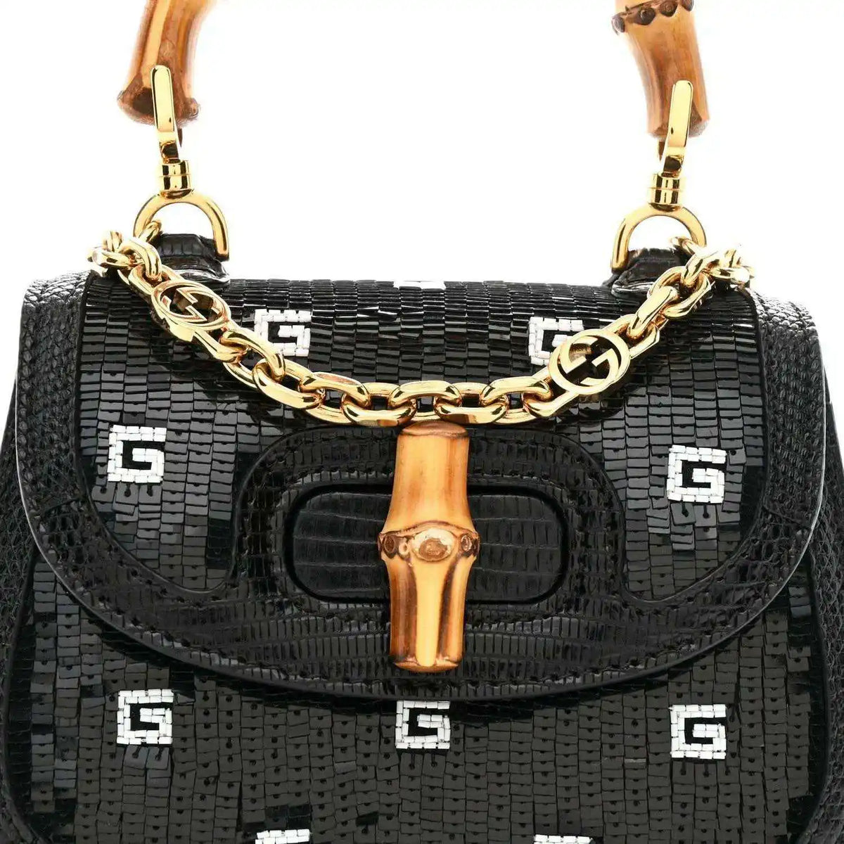 Black mini shoulder bag front view with gold chain strap, bamboo handle, and logo pattern