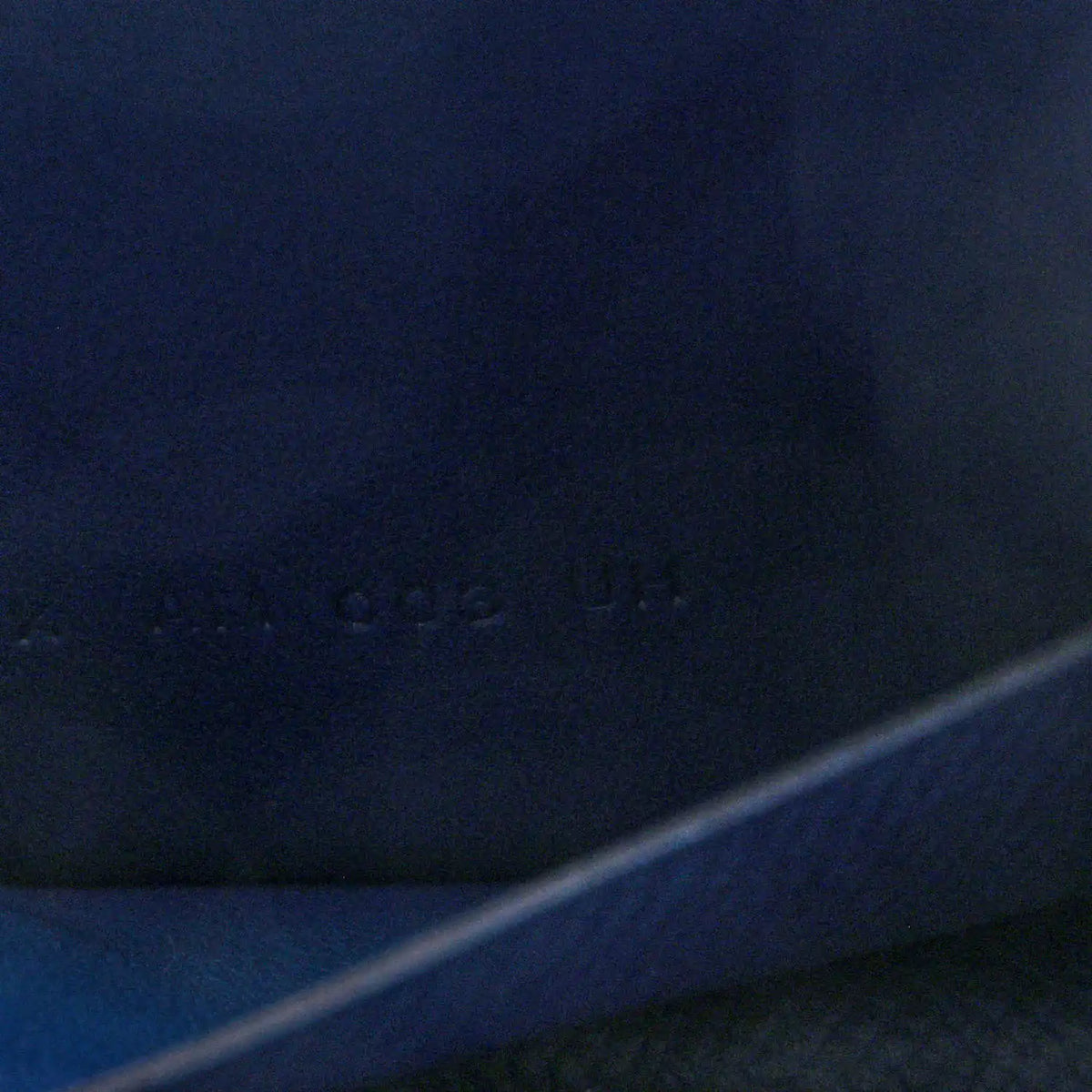 Blue leather slim wallet close-up with faint embossed mark