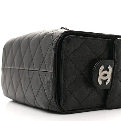 Black quilted mini shoulder bag with chain strap and rounded front pocket, side close-up.