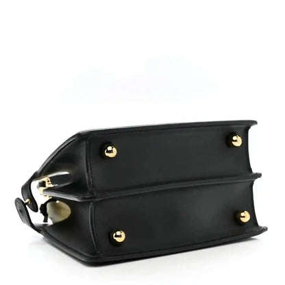 Black leather satchel with curved top, gold logo studs, and shoulder strap
