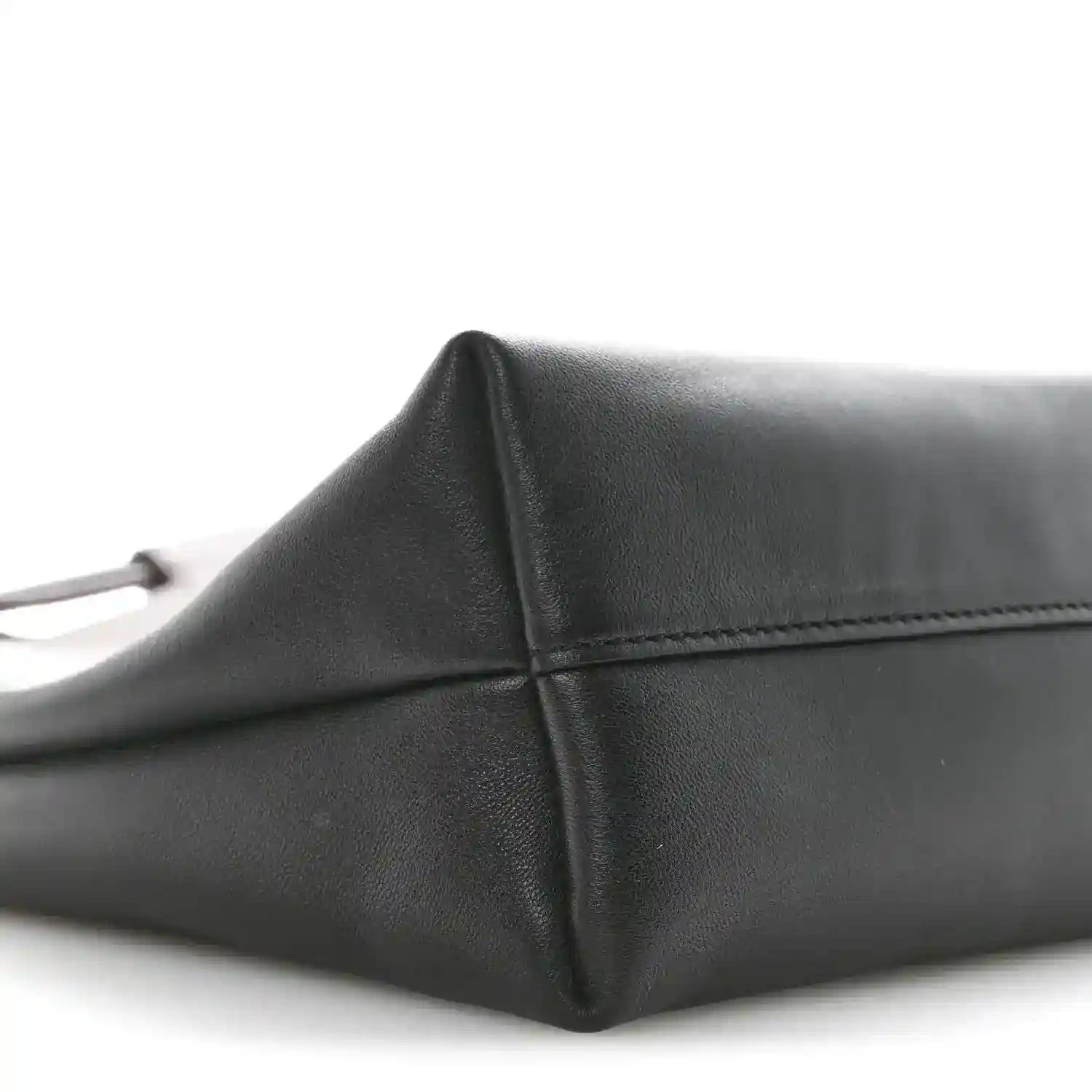 Black leather tote bag corner detail with seam stitching and angled side.