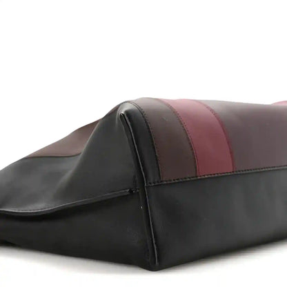 Clutch bag side close-up with burgundy, taupe, and black striped leather bands