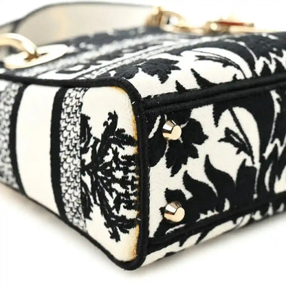 Mini embroidered canvas bag side panel with black floral print and striped white sections