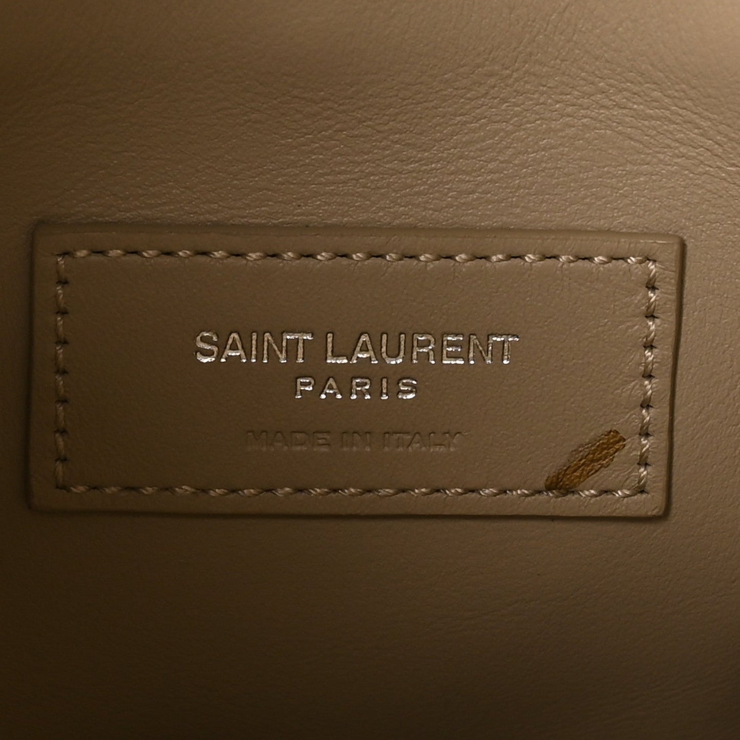 Saint Laurent Paris leather brand label with stitching on a beige bag