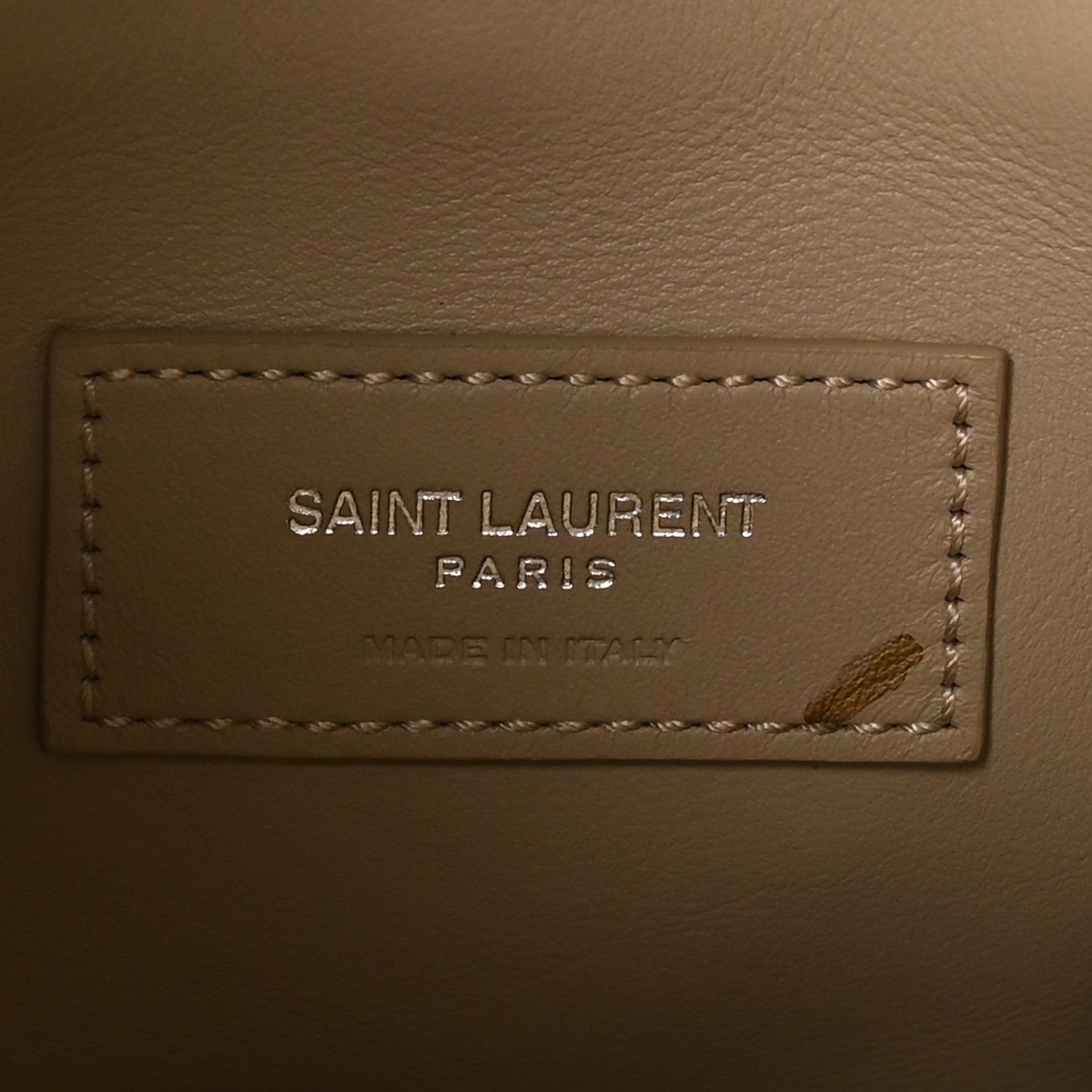 Saint Laurent Paris leather brand label with stitching on a beige bag