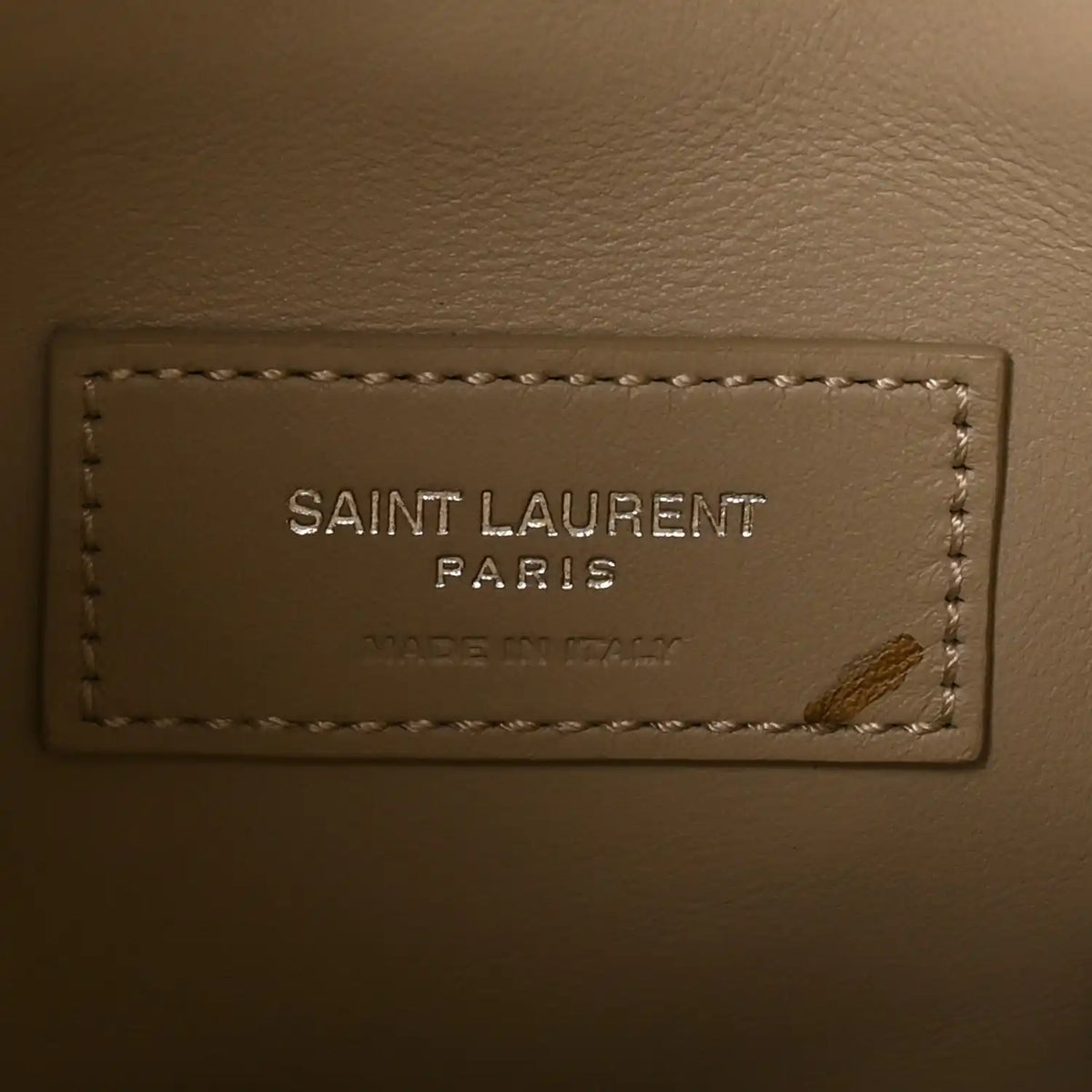 Saint Laurent Paris leather brand label with stitching on a beige bag