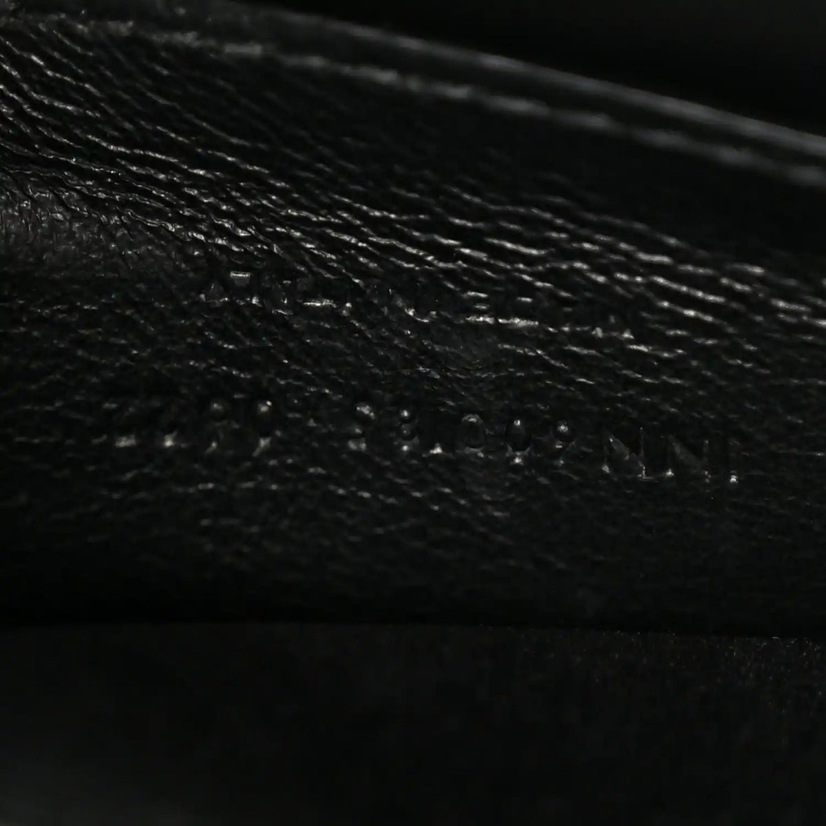 Leather satchel interior panel detail in dark color, textured grain and stitching