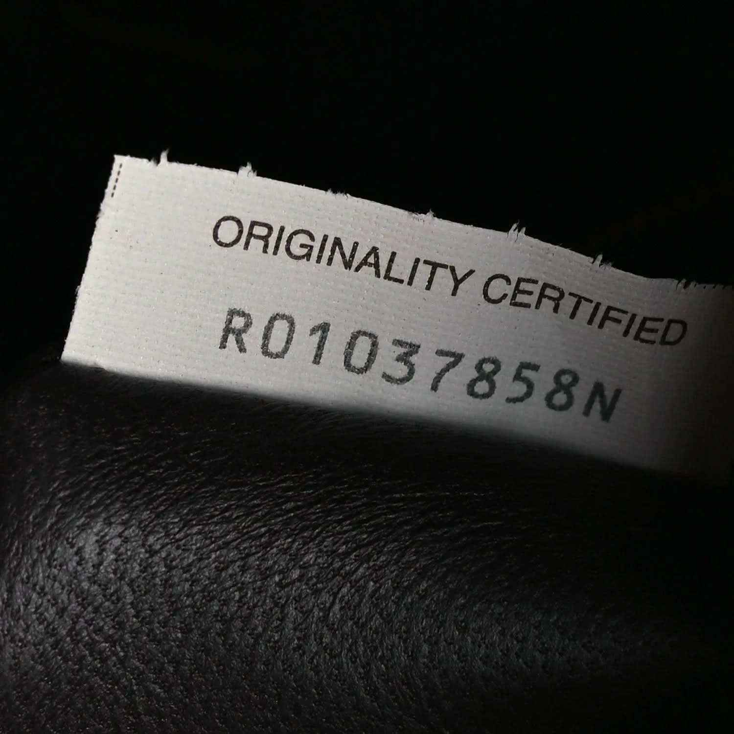 Leather authenticity tag reading “ORIGINALITY CERTIFIED” with reference number