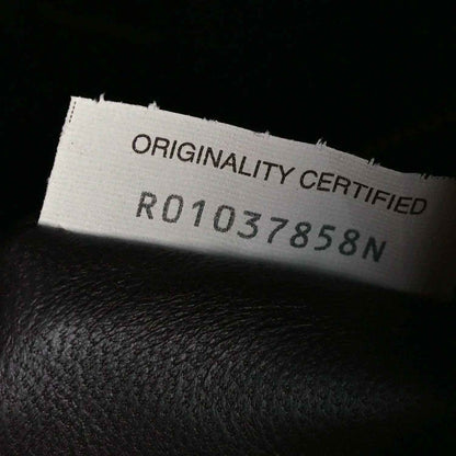 Leather authenticity tag reading “ORIGINALITY CERTIFIED” with reference number