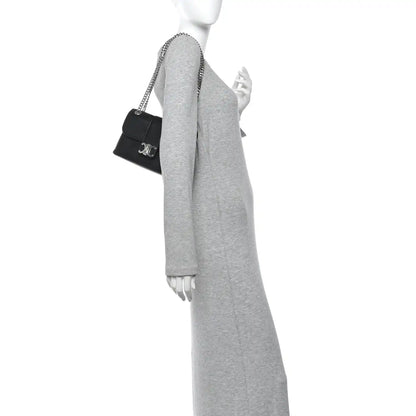 Black leather shoulder bag with chain strap, worn crossbody by model
