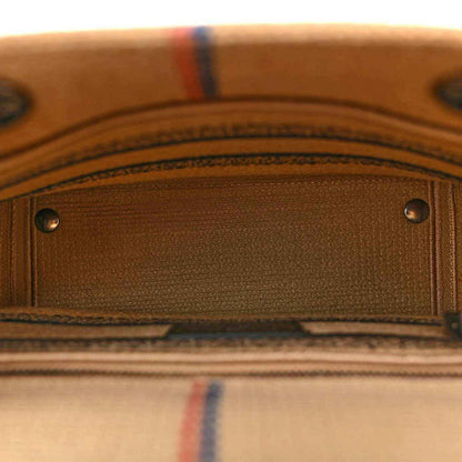 Close-up of jute canvas bag front pocket with silver rivets and striped edging.