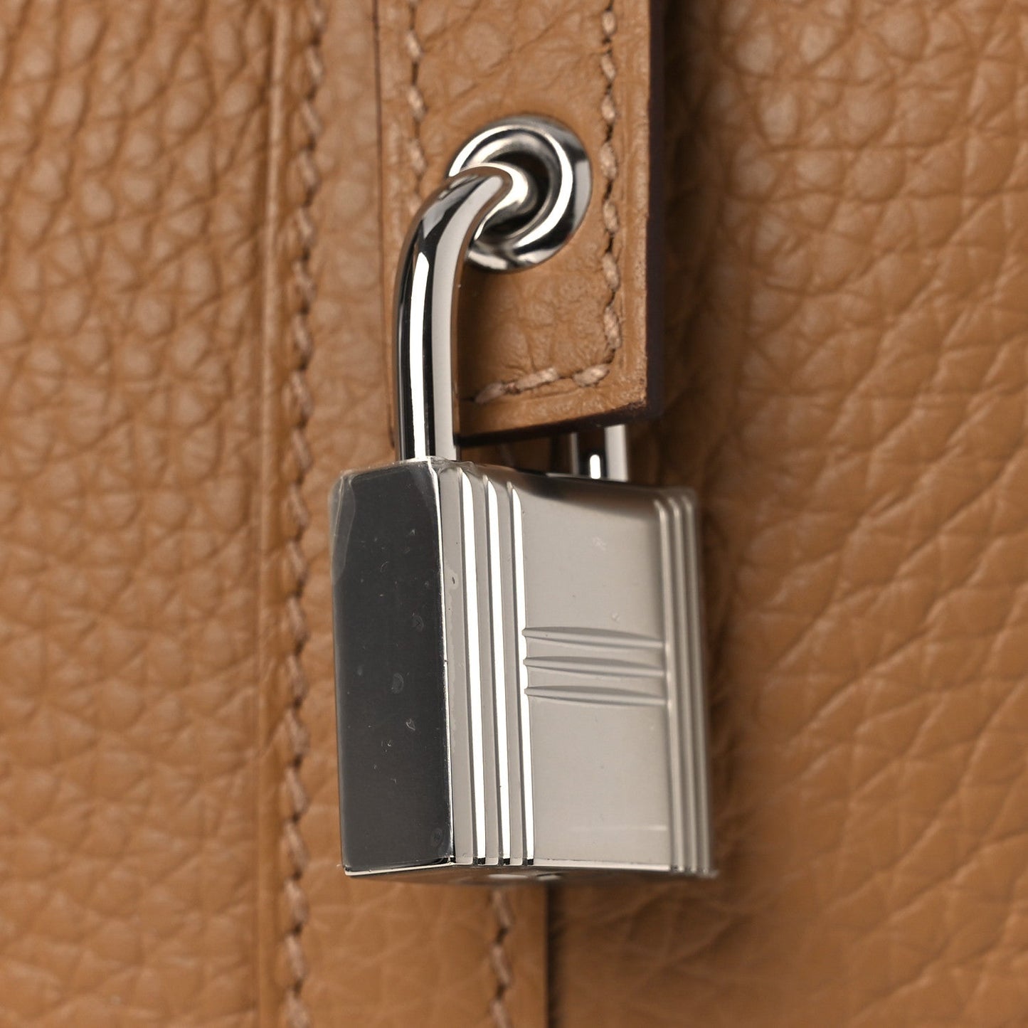 Tan leather bucket bag with silver lock clasp and stitched edge detail.