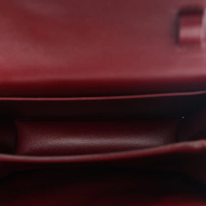 Burgundy leather interior lining view under the front flap of a structured bag.