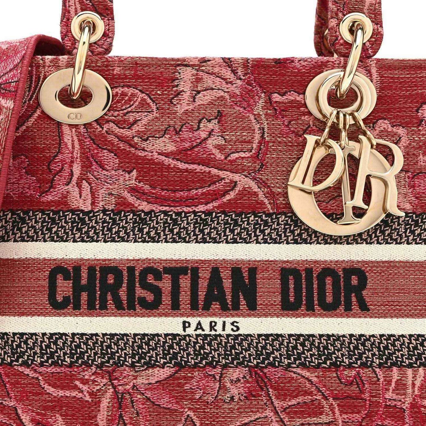 Pink embroidered canvas handbag front with gold charms and “CHRISTIAN DIOR PARIS” stripe