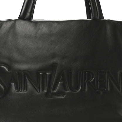 Black SAINT LAURENT embossed logo on lambskin wide puffer tote front panel.