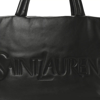 Black SAINT LAURENT embossed logo on lambskin wide puffer tote front panel.