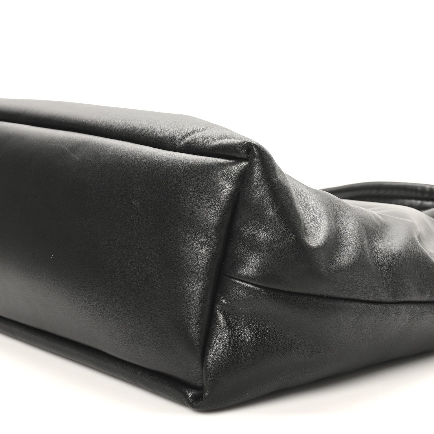 Black lambskin tote side panel close-up with top handle base and seam detail.
