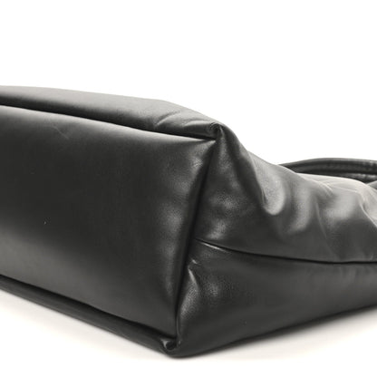 Black lambskin tote side panel close-up with top handle base and seam detail.
