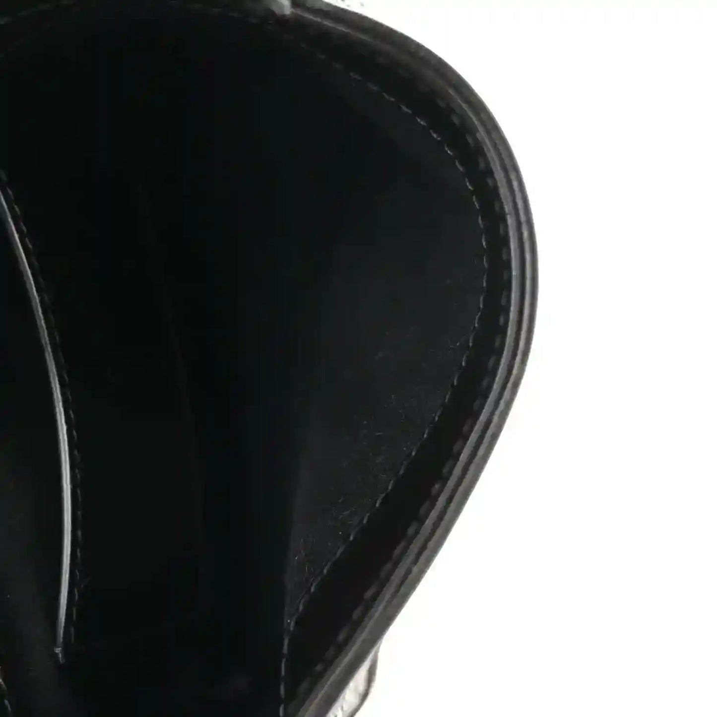 Close-up of black leather hobo bag edge and curved side panel stitching.