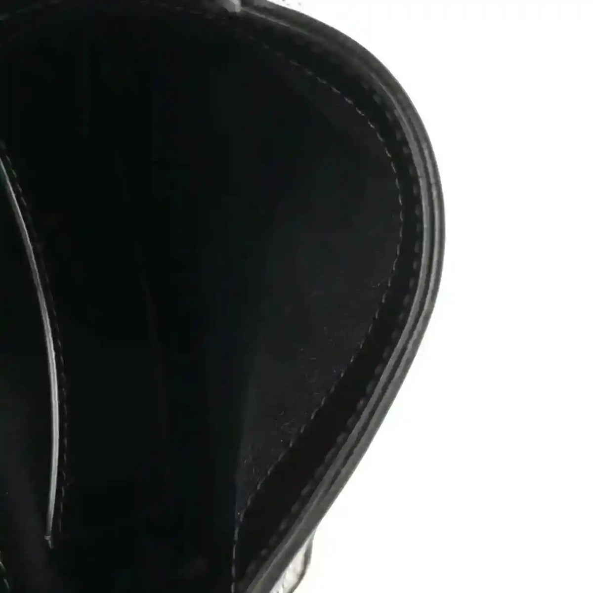 Close-up of black leather hobo bag edge and curved side panel stitching.