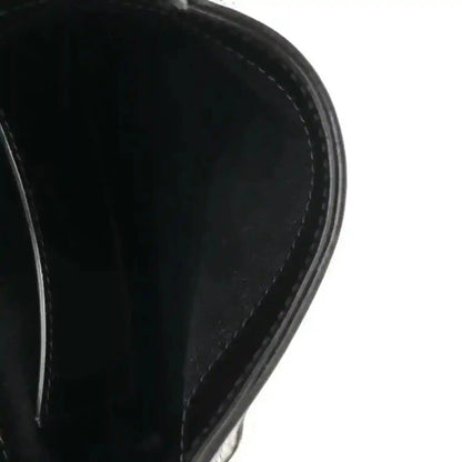 Close-up of black leather hobo bag edge and curved side panel stitching.
