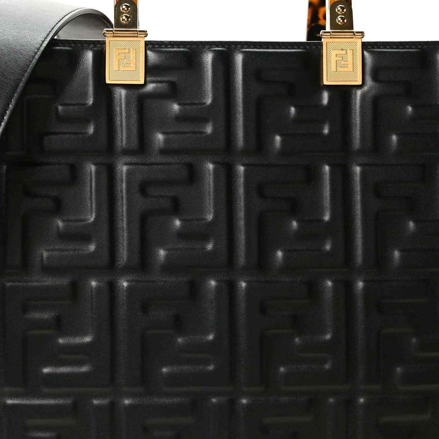 Black embossed leather tote bag close-up of FF pattern and gold handle hardware