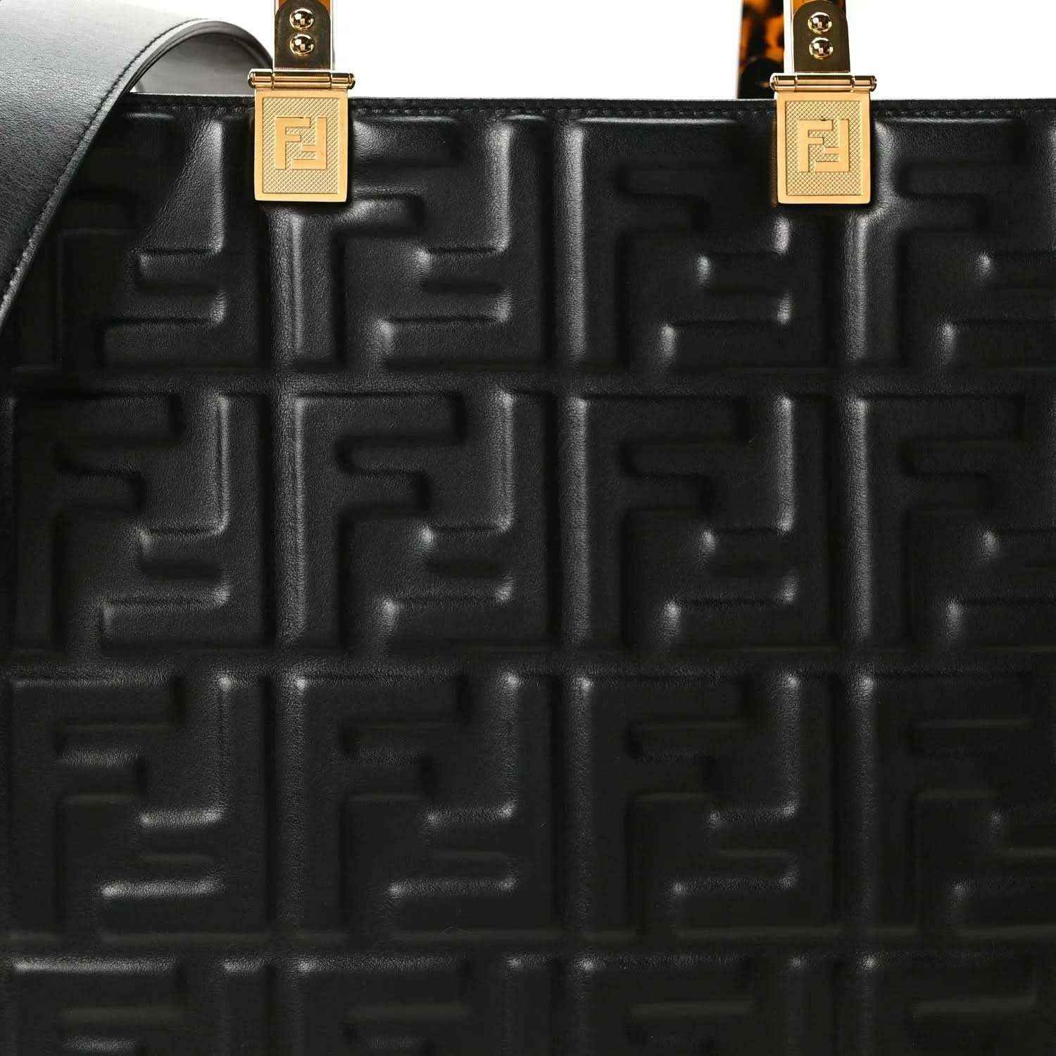 Black embossed leather tote bag close-up of FF pattern and gold handle hardware