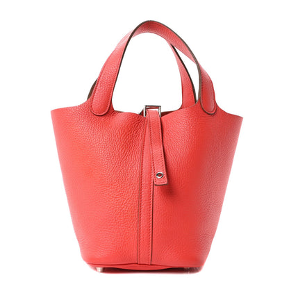 Red leather tote bag with top handles and front vertical clasp tab