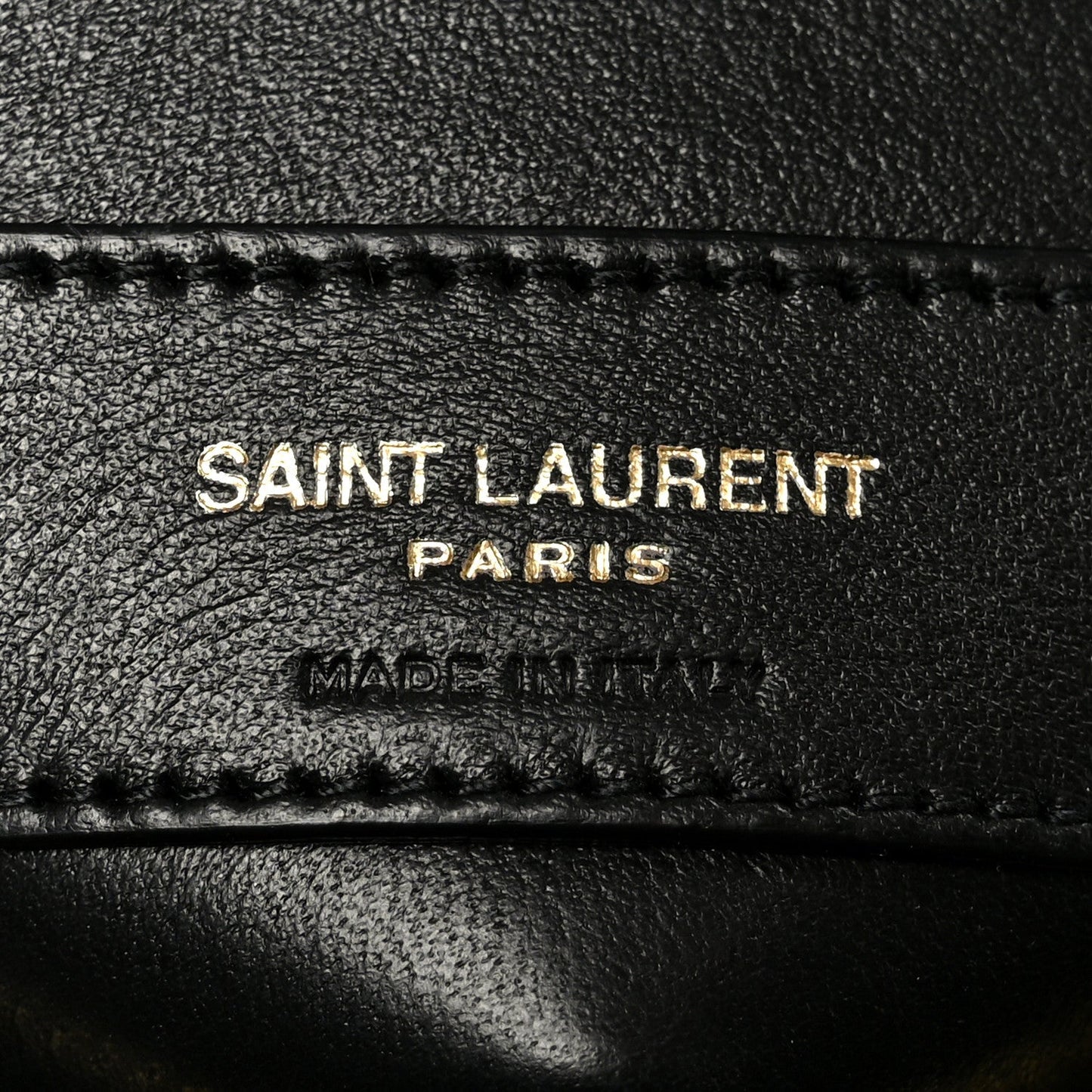 SAINT LAURENT PARIS and MADE IN ITALY text on black leather patch with stitching.
