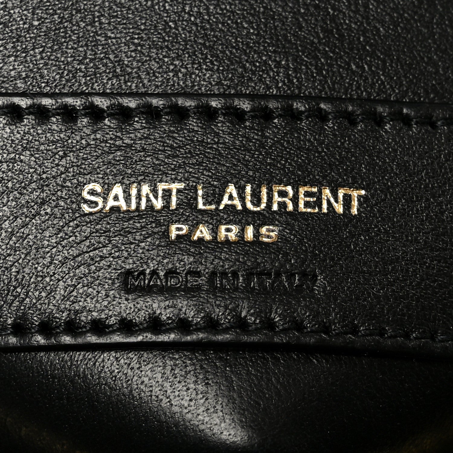 SAINT LAURENT PARIS and MADE IN ITALY text on black leather patch with stitching.