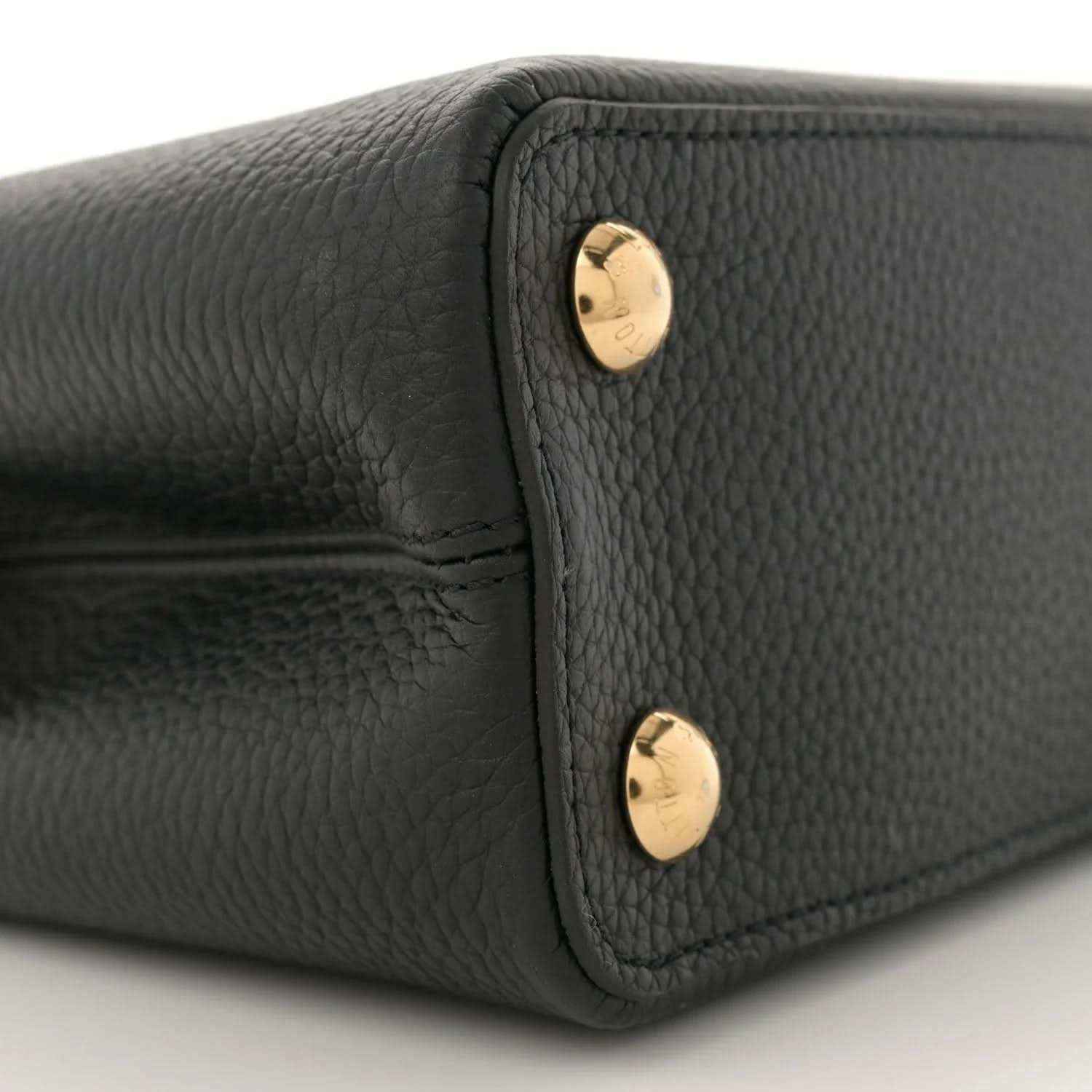 Black leather mini bag side panel with two gold snap buttons, close-up