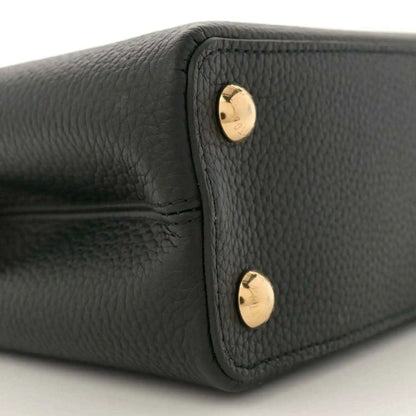 Black leather mini bag side panel with two gold snap buttons, close-up