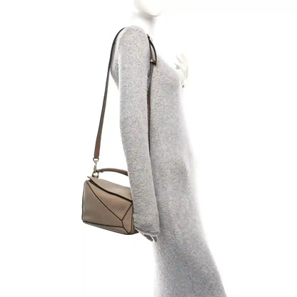 Small Puzzle bag side view with adjustable strap, grained sand leather