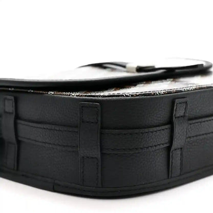 Black leather messenger bag corner with top strap loop and structured paneling