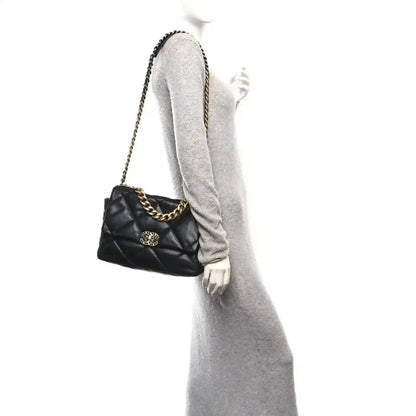 Black quilted leather flap bag worn on shoulder, gold-tone chain and logo