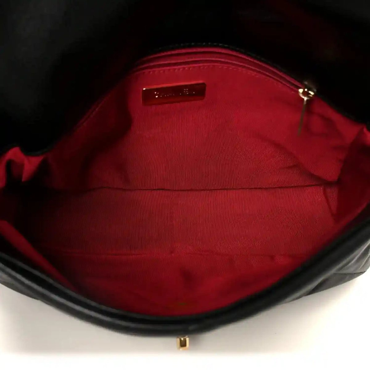Black leather flap bag interior with red lining and small metal label