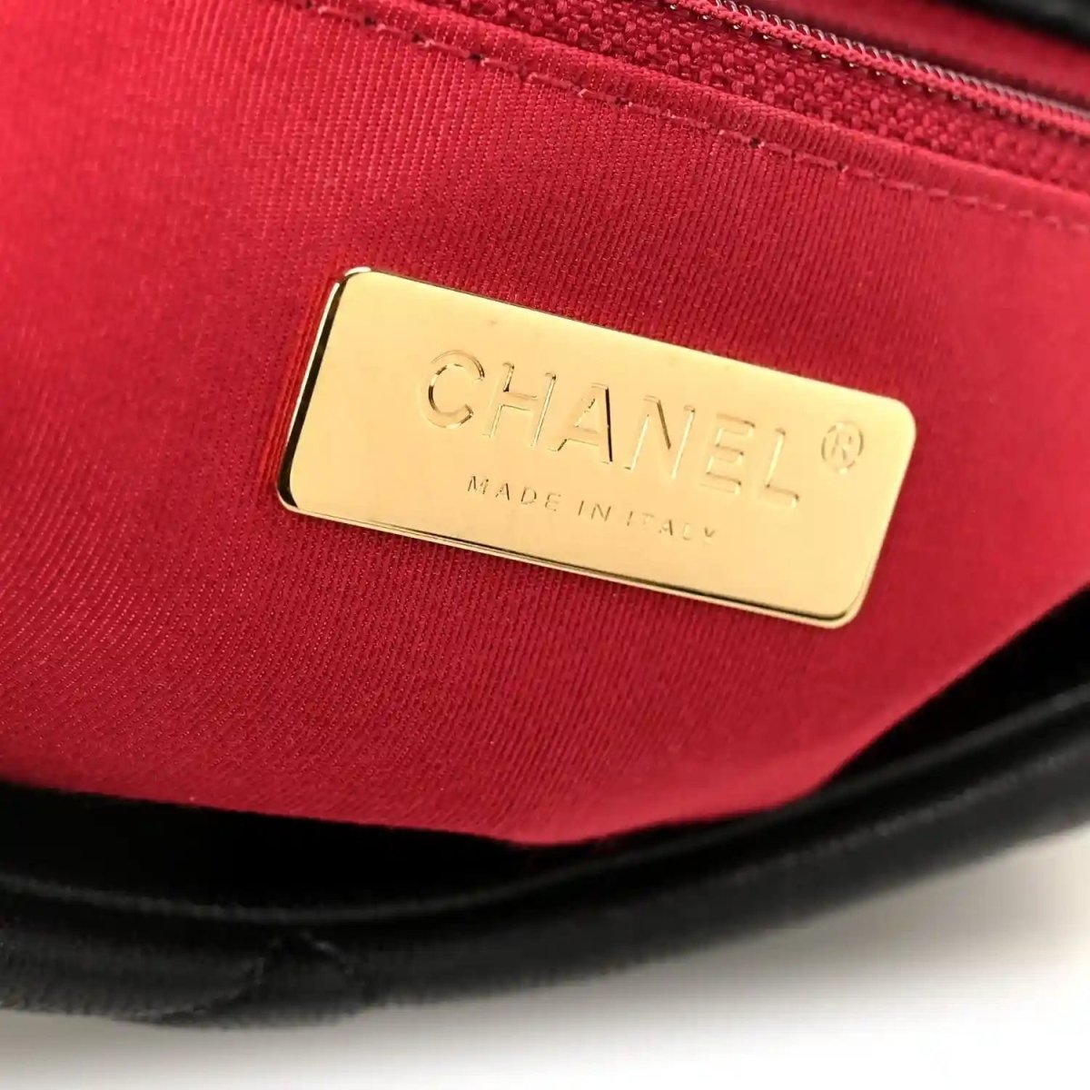 Red-lined interior of black flap bag with gold Chanel logo label