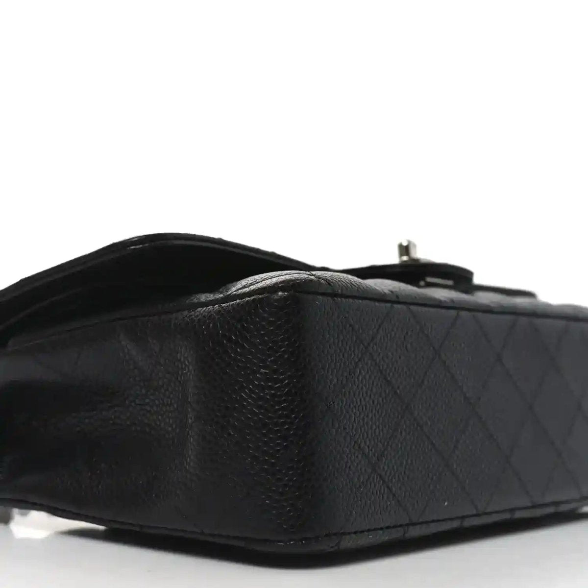 Black quilted leather flap bag side view with chain strap and stitched edge