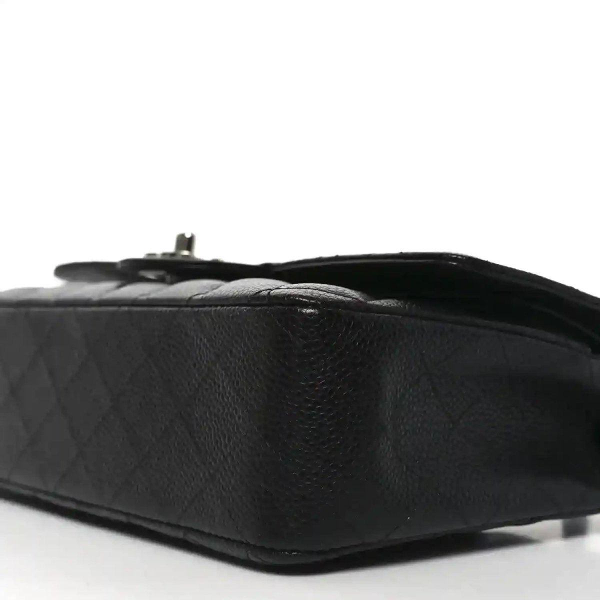 Black quilted leather flap bag side view with turn-lock hardware detail