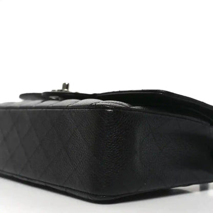 Black quilted leather flap bag side view with turn-lock hardware detail