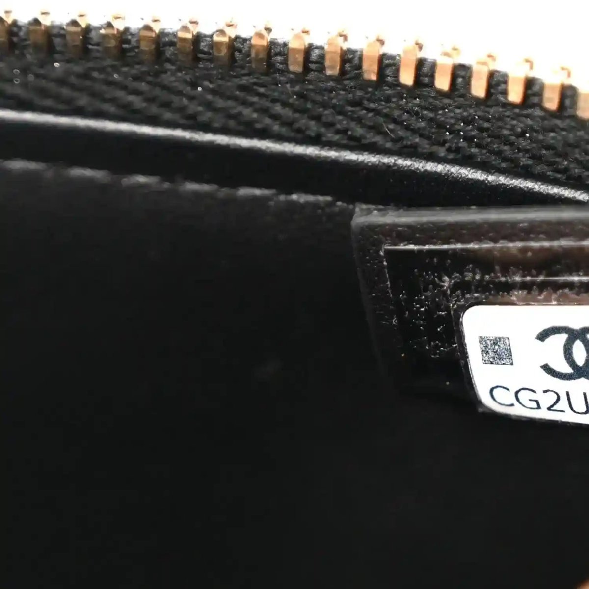 Black leather bag close-up of gold zipper hardware and interior label