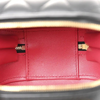 Red-lined interior of a black quilted vanity chain case with gold zipper