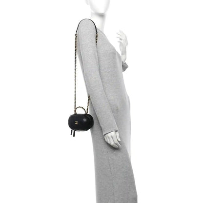 Black chain vanity case with gold CC logo, carried crossbody on a person