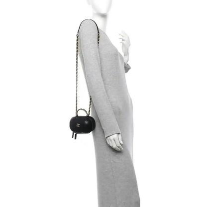 Black chain vanity case with gold CC logo, carried crossbody on a person