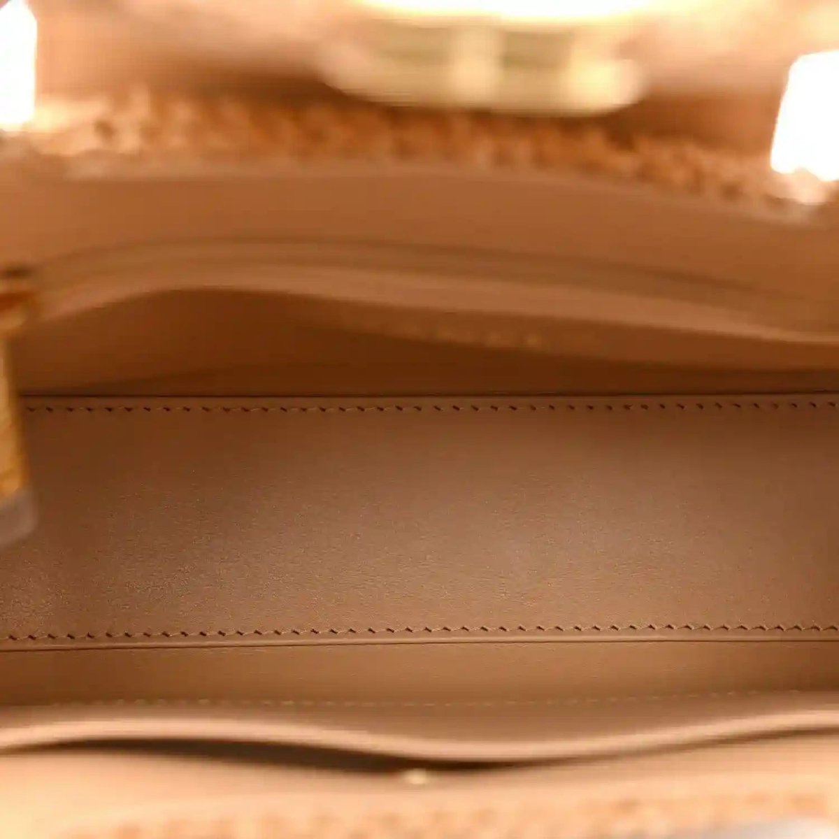 Beige fabric-lined interior of a Chanel flap bag with stitched edge